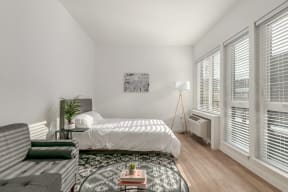 a bedroom with a bed and windows with white blinds