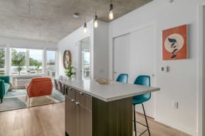 a kitchen with an island and a living room with a dining table and chairs