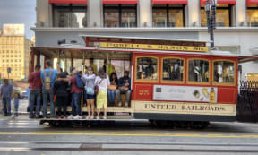 a group of people riding a streetcar on a city street