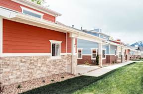 a row of houses with red and blue siding and a sidewalk