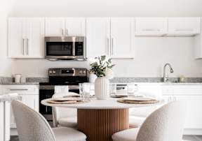 a kitchen with white cabinets and a table and chairs
