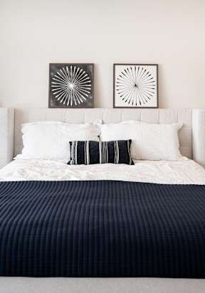 a bedroom with a bed and pillows and pictures on the wall