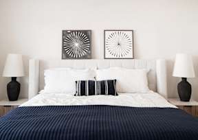 a bedroom with a bed and two paintings on the wall
