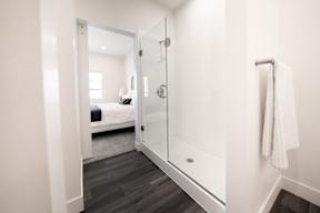 a ensuite bathroom with a glass shower and a bed