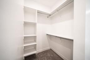 a walk in closet with empty shelves in a white room