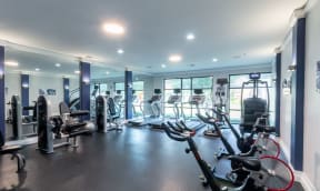 a gym with cardio equipment and weights in a building with windows