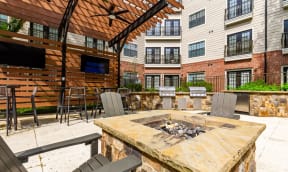 a patio with a fire pit in front of an apartment building