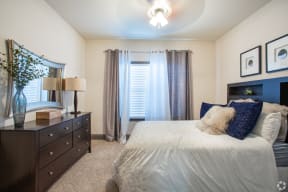 a bedroom with a large bed and a dresser and window