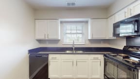 a kitchen with white cabinets and black counter tops and a sink