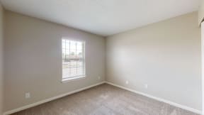 an empty bedroom with a window in the corner