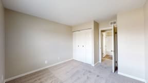an empty bedroom with a closet and a door to a hallway