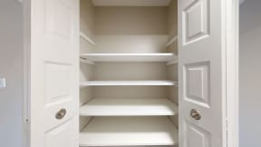 an empty closet with white shelves and a white door