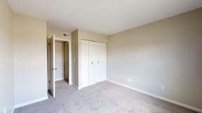an empty bedroom with a closet and a door to a hallway
