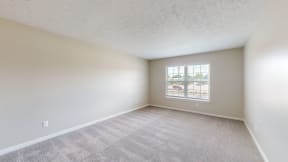 an empty living room with a window and white walls