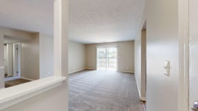 an empty living room and hallway with a door to a balcony