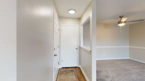 the living room and hallway of a manufactured home with white walls and wood flooring