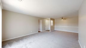 an empty living room with white carpet and a door to a hallway