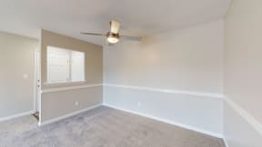 an empty living room with a ceiling fan and a window
