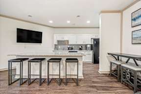 A kitchen with a bar area and a television mounted on the wall.