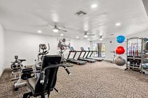 A gym room with a variety of exercise equipment.