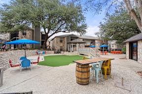 A backyard with a green lawn, a barrel table, and chairs.
