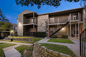 A modern two-story apartment building with a balcony on the second floor.