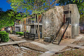 A modern house with a stone wall and a tree in front.