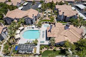 A large swimming pool surrounded by houses and palm trees.