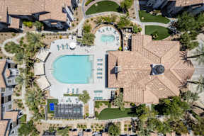 A large swimming pool surrounded by a tiled patio and a small building.