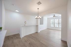 A spacious room with a white counter and a chandelier hanging from the ceiling.