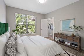 A bedroom with a large bed and a window with blinds.