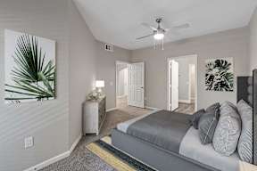 A bedroom with a bed, nightstand, and a ceiling fan.