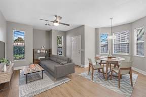 A living room with a grey couch, a coffee table, and a dining table with chairs.