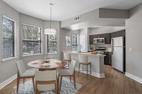 A modern kitchen with a dining table set for two.