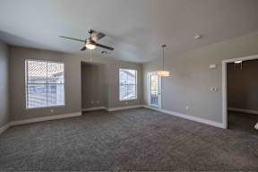 A spacious room with a ceiling fan and carpeted floor.