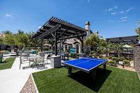 A blue table tennis table is in the middle of a grassy area.