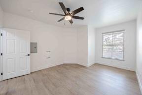 A room with a ceiling fan and a window with blinds.
