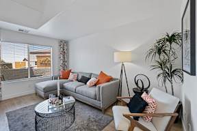 A living room with a grey couch, a coffee table, and a lamp.