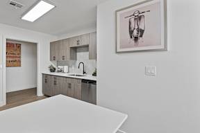 A modern kitchen with a white table and a framed picture of a scooter on the wall.