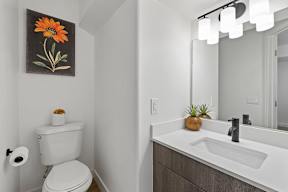A bathroom with a toilet, sink, and a flower painting on the wall.