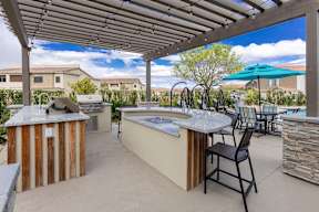 A patio with a hot tub and chairs under a roof.