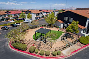 A park area with a gazebo and a fence in front of apartment buildings.