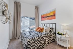 A bedroom with a large bed and a painting on the wall.