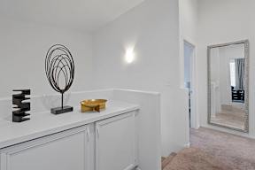 A white bathroom with a mirror and a black sculpture on the counter.