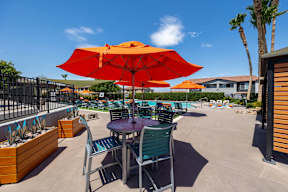 A patio with a table and chairs under an orange umbrella.