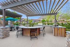 A patio with a table and chairs under a wooden pergola.