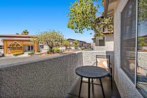 A patio with a table and chairs overlooking a street.