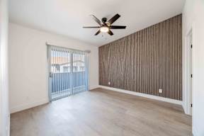 A room with a ceiling fan and sliding glass doors.