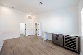A room with a wooden floor and white walls, with a built-in cabinet and a bench.
