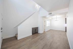 A spacious room with wooden flooring and white walls.